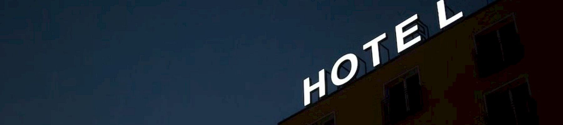 A building at night with the word "HOTEL" in bright lights on its rooftop.