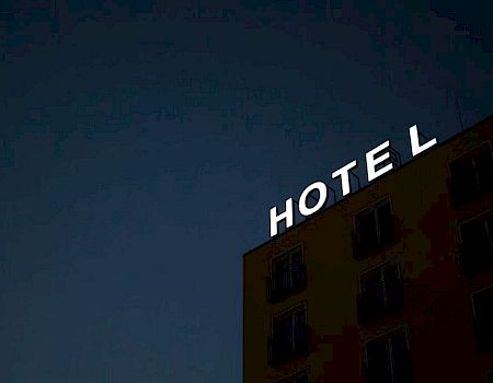 A building at night with the word "HOTEL" in bright lights on its rooftop.